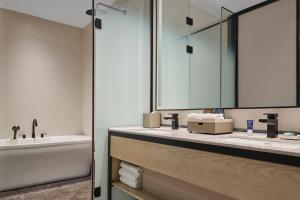a bathroom with a sink and a tub and a mirror at Four Points by Sheraton Datong Pingcheng in Datong