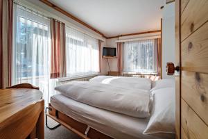 1 Schlafzimmer mit 3 Betten in einem Zimmer mit Fenstern in der Unterkunft Paradies 203 in Arosa + 1 Foto