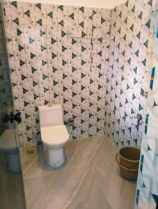 a bathroom with a toilet and a tiled wall at Heaven Residency in Munroe Island