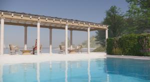 a swimming pool with a pergola and a table and chairs at Makryammos in Limenas