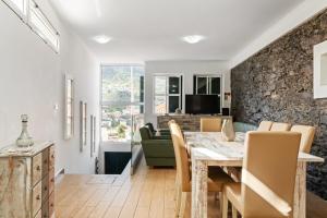 a dining room with a stone wall and a table and chairs at Casa da Avó Paraíso in Machico