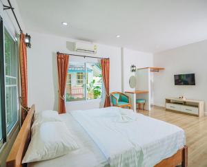 a bedroom with a bed and a desk and a television at Baan Sarika Phusuan in Nakhon Nayok