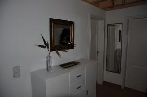 a white cabinet with a vase on it with a mirror at Ferienhaus Strandläufer in Krummhörn