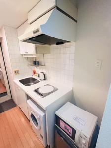 a small kitchen with a sink and a washing machine at Shinjuku West Park Inn Hanabi House in Tokyo