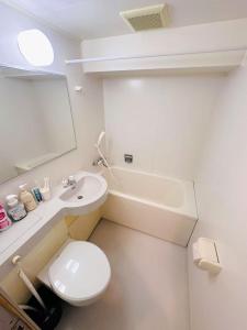 a white bathroom with a toilet and a sink at Shinjuku West Park Inn Hanabi House in Tokyo
