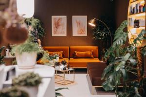 a living room with an orange couch and plants at Elements Hotel&Spa in Świeradów-Zdrój