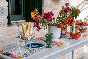 a table with flowers and wine glasses on it at Almond Blossom Cottage 1 in Philotium
