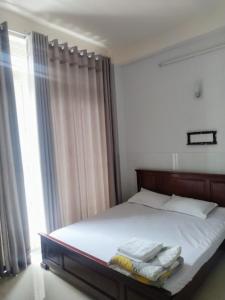 a bedroom with a bed with white sheets and a window at Kathy Hotel in Ho Chi Minh City
