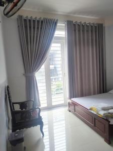 a bedroom with a bed and a window with a cat in a chair at Kathy Hotel in Ho Chi Minh City