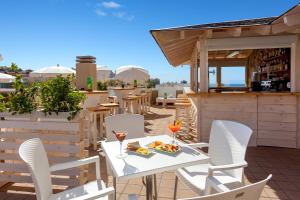 eine Terrasse mit einem Tisch und Stühlen sowie einer Bar in der Unterkunft Aparthotel Los Dragos del Sur in Puerto de Santiago