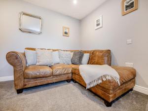 un soggiorno con divano in pelle marrone di Coed Y Gaer Annexe - Uk43776 a Llansilin