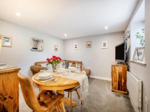 un soggiorno con un tavolo e una TV di Coed Y Gaer Annexe - Uk43776 a Llansilin