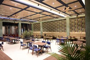 a dining room with tables and chairs and plants at Club Charholi in Lohogaon