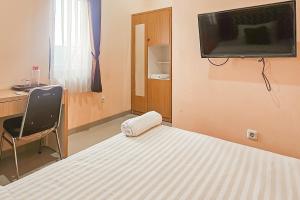 a bedroom with a bed and a television on a wall at Urbanview MJ House Syariah Bandung in Bandung