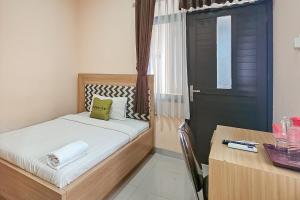 a small bedroom with a bed and a desk and a door at Urbanview MJ House Syariah Bandung in Bandung