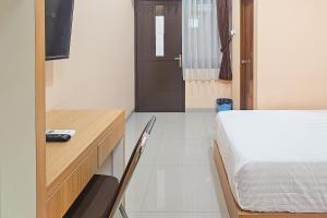 a bedroom with a bed and a desk and a door at Urbanview MJ House Syariah Bandung in Bandung +18 photos