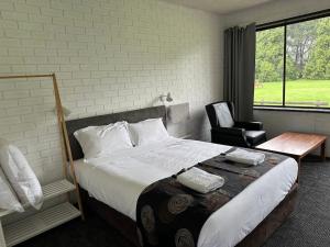 a bedroom with a large bed and a chair at The Reserve Hotel in Sale