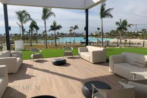 a patio with white couches and chairs and a pool at Villa Almendro Santa Rosalia Lake and Life Resort by PREMIUM SPAIN PROPERTIES in Torre-Pacheco