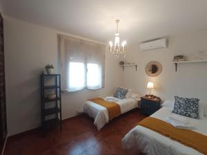a bedroom with two beds and a window and a chandelier at Casa Rural Vista Castillo in Almonacid de Toledo +47 photos