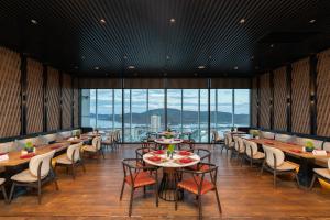 a restaurant with tables and chairs and large windows at TMS Quy Nhơn View Biển in Quy Nhon