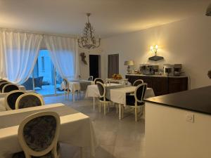 a dining room with white tables and chairs at Le Bonheur de l'Instant in Saint-Médard-dʼAunis