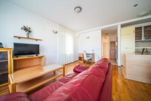a living room with a red couch and a television at Pervanovo Apartments with Free Parking in Dubrovnik