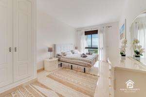 a white bedroom with a bed and a window at Golfer's paradise - 2BR with garage and pool in San Roque