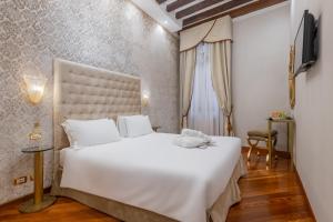 a bedroom with a large white bed and a television at Cà dell'arte Suite in Venice