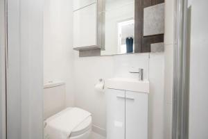 a white bathroom with a toilet and a sink at Gilded Nooks in Croydon +35 photos