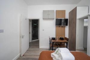 a room with a bed and a table and a kitchen at Gilded Nooks in Croydon