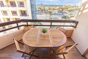 Una mesa y sillas de madera en un balcón. en EL AQUARIO - Urbanización Eurovosa VISTAS AL MAR 1 DORMITORIO, en La Manga del Mar Menor