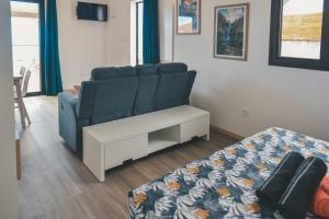 a living room with a blue couch and a bed at OISEAUX DU PARADIS - Bungalow 2 voyageurs in Saint-Leu