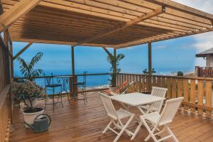 a deck with a table and chairs and the ocean at OISEAUX DU PARADIS - Bungalow 2 voyageurs in Saint-Leu