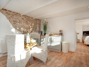 a kitchen and dining room with a glass table and chairs at Harlequin Cottage in St Austell