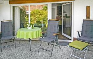 a table with three chairs and a table with a green table cloth at Ferienhaus Dranske Auf Rügen in Dranske