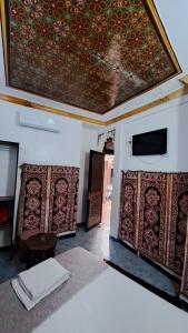 a room with a bed and a tv and a ceiling at Hotel Riad Fantasia in Marrakesh