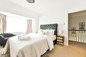 a white bedroom with two beds and a chair at House with Garden Next Wembley Stadium Free Parking in London