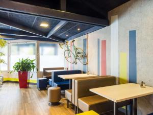 a restaurant with tables and a bike hanging from the ceiling at ibis budget Issy Les Moulineaux Paris Ouest in Issy-les-Moulineaux