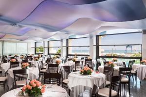 ein Bankettsaal mit Tischen und Stühlen mit Blumen in der Unterkunft Hotel Baltic Riccione-Fronte Mare in Riccione