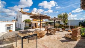 une maison avec un patio avec des tables et des parasols dans l'établissement Cortijo del Coco 1 Fuente de Piedra by Ruralidays, à Fuente de Piedra