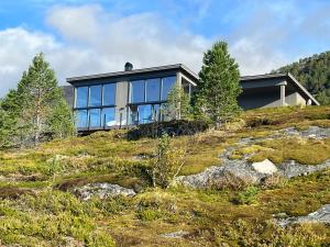 une maison au sommet d'une colline avec du verre dans l'établissement Efjord and Stetind Resort - Cabin Stetind, à Ballangen