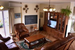 a living room with leather furniture and a flat screen tv at Blougans B&B in Gansbaai