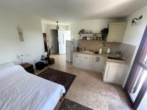 Jaffa Rooftop Studio with Sea Views في تل أبيب: غرفة نوم مع سرير ومطبخ مع دواليب بيضاء