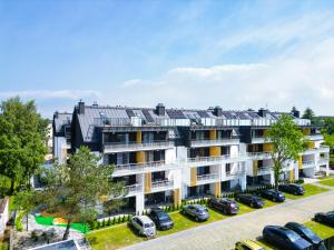 an apartment building with cars parked in a parking lot at DELUXE SAND APARTMENT & SPA Posesja Plażowa by POSESJA APARTAMENTY in Grzybowo