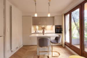 a kitchen with a white counter and a table and chairs at Charmant Appart, terrasse verdoyante, proche Paris in Saint-Maur-des-Fossés