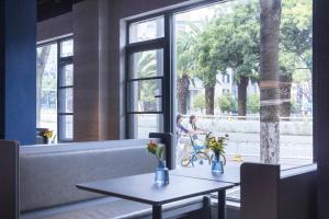 two tables in a restaurant with a woman and a child looking out the window at Atour Light Hotel Kunming Dianchi Road South Asia Style First City in Kunming