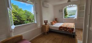 a small bedroom with a bed and two windows at Villa M'Bay in Sainte-Marie