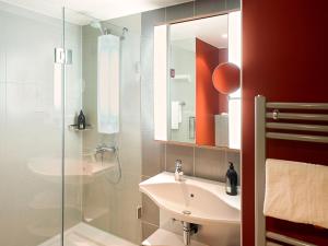 a bathroom with a sink and a glass shower at Aparthotel Adagio Köln City in Cologne