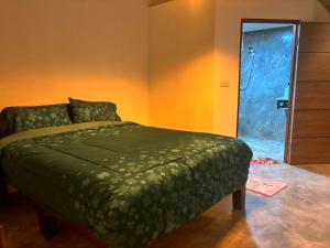 a bedroom with a green bed and a shower at กานต์รีสอร์ต เชียงดาว in Ban Thung Kala
