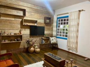 a living room with wooden walls and a television at Cantinho Almeida in Tiradentes +37 photos